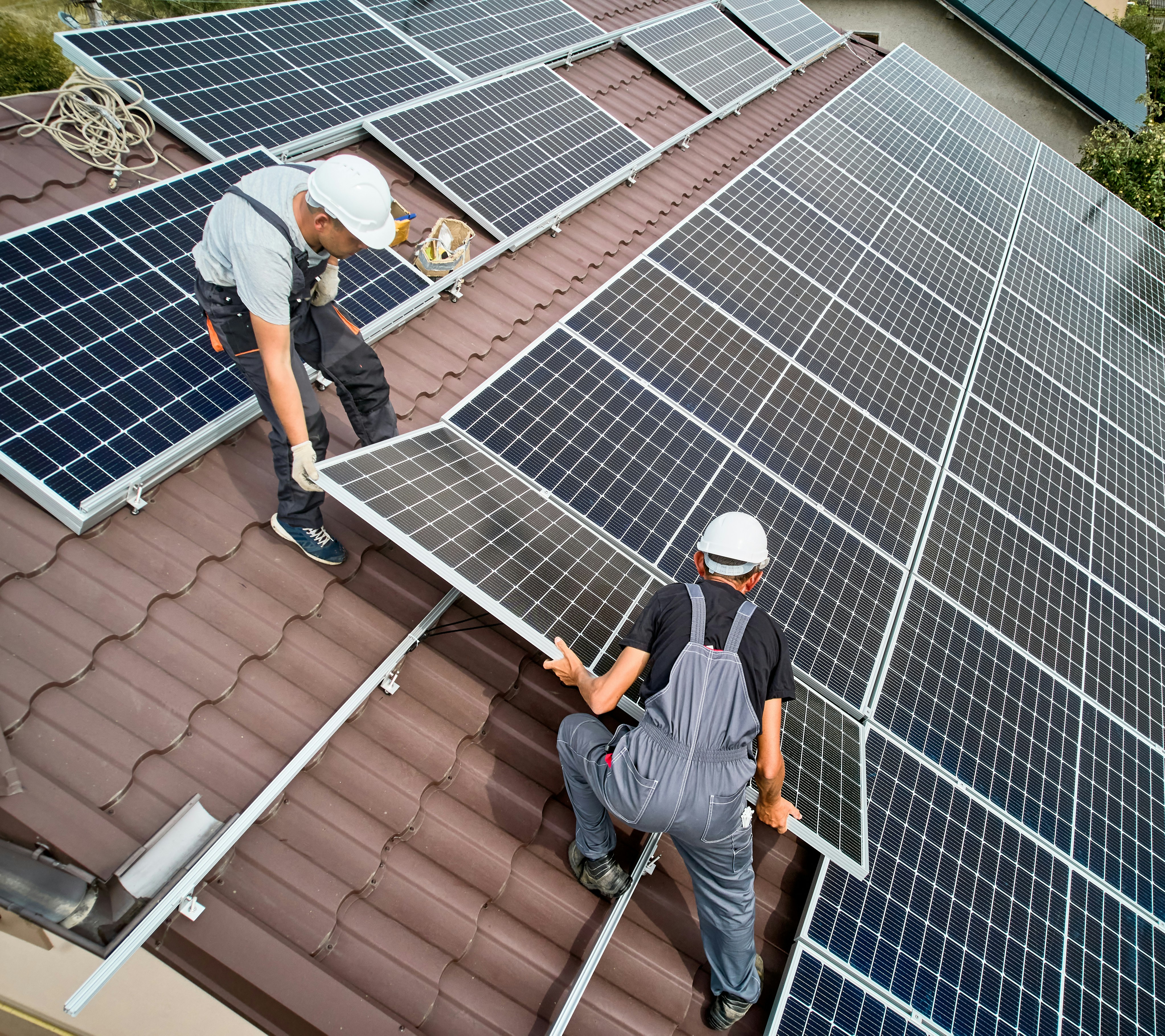 Installers fitting solar panels on a house roof
